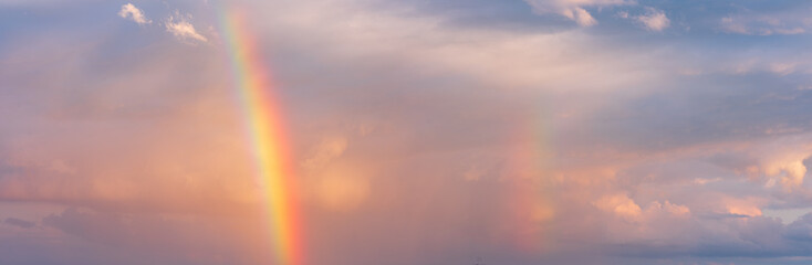 Wall Mural - Panoramic background of stormy sky with rainbow and dramatic clouds at sunset