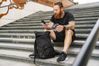 © Drobot Dean - Young handsome bearded tattooed redhead man with bottle and phone