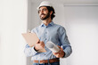 © Westend61 - Happy engineer wearing hardhat holding blueprints in office