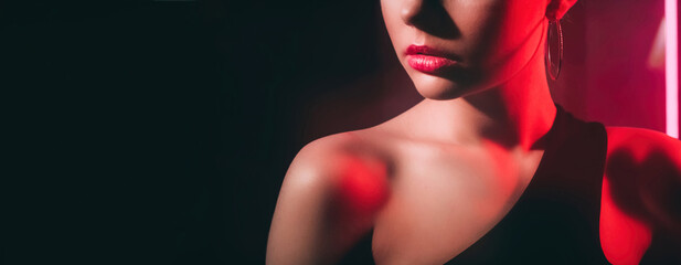 Wall Mural - Fashion beauty. 90s look. Retro vogue. Red color neon light cropped profile portrait of unrecognizable woman model face on dark black copy space background.