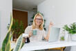 © Westend61 - Happy freelancer with tea cup and laptop sitting at desk