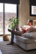 © Westend61 - Man with smart phone sitting on sofa at home