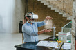 © Westend61 - Businessman wearing VR glasses gesturing with model house on desk at construction site
