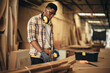 © vacancylizm - Carpenter man attend to making masterpiece woodworks handcrafted furniture fine measure in wood workshop.