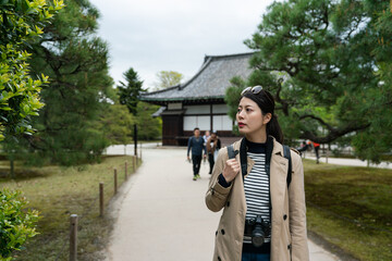 Wall Mural - curious asian Japanese female backpacker noticing something and looking away into space while walking around Honmaru garden at Motorikyu Nijyojo nijo castle in Kyoto japan