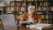 © Synthex - Diligent asian student taking online classes, taking notes, sitting at library