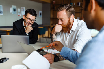 Wall Mural - Multinational businessmen using laptops and documents working at office