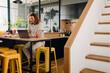 © Drobot Dean - Young man sitting by table while working on laptop in office kitchen