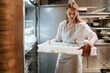 © Drobot Dean - Young blonde woman putting food in refrigerator working in kitchen