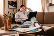 © Drobot Dean - Smiling asian woman working on laptop while sitting on couch