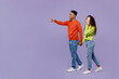 © ViDi Studio - Full body side view young couple two friend family man woman of African American ethnicity in casual clothes hold hands walk go together point finger aside isolated on pastel plain purple background