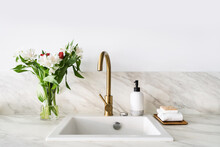 Modern Sink, Water Tap And Flowers On White Wall Background Indoors