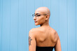 © VISTA by Westend61 - Woman with shaved head in front of blue wall