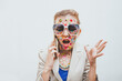 © VISTA by Westend61 - Frustrated woman with stickers on face talking on mobile phone in front of white background