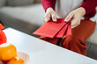 Asian Woman giving red envelope for Lunar New Year celebrations. Hand hold red packet