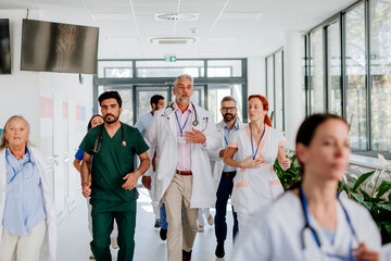 Young stressed doctors running at hospital corridor.