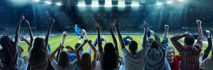 Wall Mural - Back view of football, soccer fans emotionally cheering their team at crowded stadium at evening time. Diverse group. Concept of sport, hobby, leisure time, football