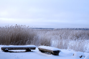 Snowy landscape. The park two benches covered with white thick snow. Winter day in the recreation area. No one person. Cold black and white monochrome background.