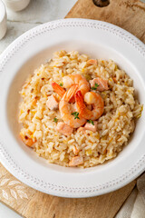 Poster - Risotto with prawns, salmon, leek and tangerine. Rice dish. White plate on a light background.  Directly above.