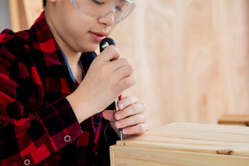 Wall Mural - Close up lovely Asian carpenter boy practice skill of screw knot on woodworking table carpentry shop