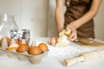 A woman in an apron prepares dough for baking at home. Rolling out and preparing dough for baking.