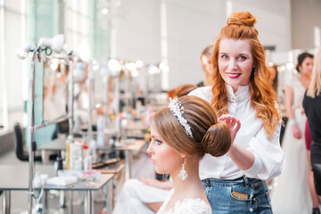 Competition among bridal hair stylists. The hairdresser makes a wedding hairstyle, looks at the camera and smiles