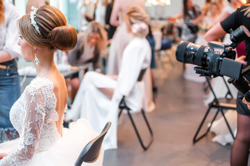 Competition among bridal hair stylists. Videographer shoots a model in a wedding dress, with hair and makeup