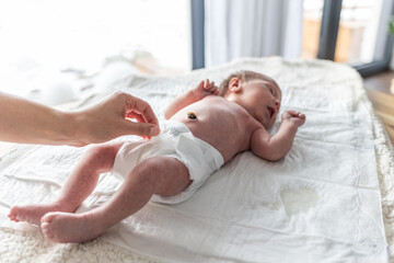 Wall Mural - Newborn baby screaming while mother puts a diaper on the changing table