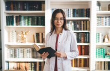 Positive Medical Worker Standing With Book In Library