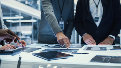 Leinwandbilder - Close Up Footage with a Diverse Anonymous Team of Industrial Engineers Gathered Around Table at a Factory Meeting, Discussing High Tech Equipment Blueprints. Focus on Hands.