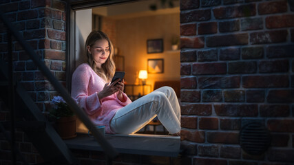 Poster - White Woman Using a Smartphone while Sitting on a Windowsill in Brooklyn Style Brownstone House. Young Female Browsing Internet, Staying Connected, Posting on Social Media Platforms