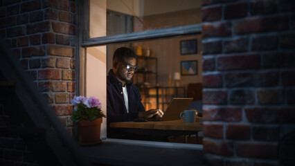 Poster - Portrait of Black Productive Young Man Working on Laptop from Home at Night. Cyber Security Specialist Checking Startup Website Protocol from Distance Using Internet. Information Technology Expert