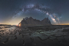Ice Pieces On Black Sand Beach Against Mountains Under Starry Sky At Night