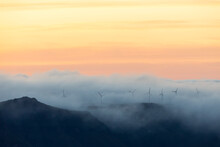 Mountainous Area With Mist And Wind Turbines