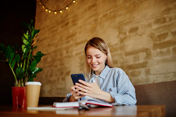 Smiling woman surfing smartphone while sitting in cafe