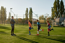 Kids Practicing Soccer On Grass Field Under Football Coach Control