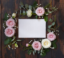 Horizontal Card Between Pink And Cream Roses On Brown Wood Top View, Wedding Mockup