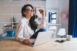 © BullRun - Happy woman sitting at table with computer surfing internet spending leisure time