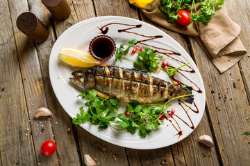 grilled trout on a white plate top view on wooden table