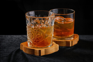 Two glasses of whiskey with ice, on a wooden board