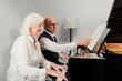 © Henko Studio - Older couple studying piano together and reading music sheet