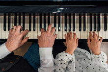 Close-up Of Senior Piano Student Hands With Her Granddaughter Playing The Piano