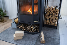Fuel Briquettes Made Of Pressed Sawdust For Kindling The Furnace - Economical Alternative Eco-friendly Fuel For The Fireplace In The House. Firewood Is Burning In The Oven In The Interior