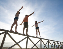 Father And Teen Daughters Balance On Top Of Fence