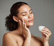 © K Abrahams/peopleimages.com - Black woman, face and skincare cream for beauty wellness shine, cosmetics dermatology and salon spa product in studio. African girl hands, facial moisturizer and spf sunscreen or luxury makeup glow
