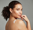 © K Abrahams/peopleimages.com - Portrait, back and woman with cream, skincare and dermatology for wellness, health and against grey studio background. Latino female, girl and lotion for cosmetics, natural beauty and smooth skin