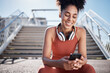 © Alexis S/peopleimages.com - Fitness, phone and black woman in city on break on social media, texting or web browsing after exercise. Sports, cellphone and happy female athlete by stairs with 5g mobile smartphone for networking.
