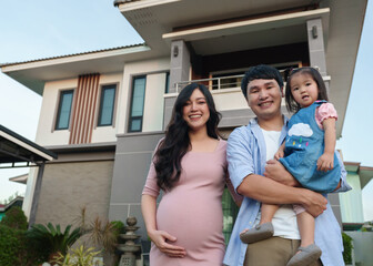 Wall Mural - happy family standing outside house, husband and pregnant wife and baby girl