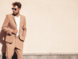 © halayalex - Handsome confident stylish hipster lambersexual model.Sexy modern man dressed in elegant beige suit. Fashion male posing in the street in city at sunset. In sunglasses. Near wall