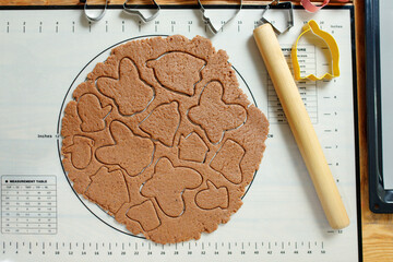 Wall Mural - Flat lay of rolled dough for homemade cookies with squeezed cookies of various shapes.